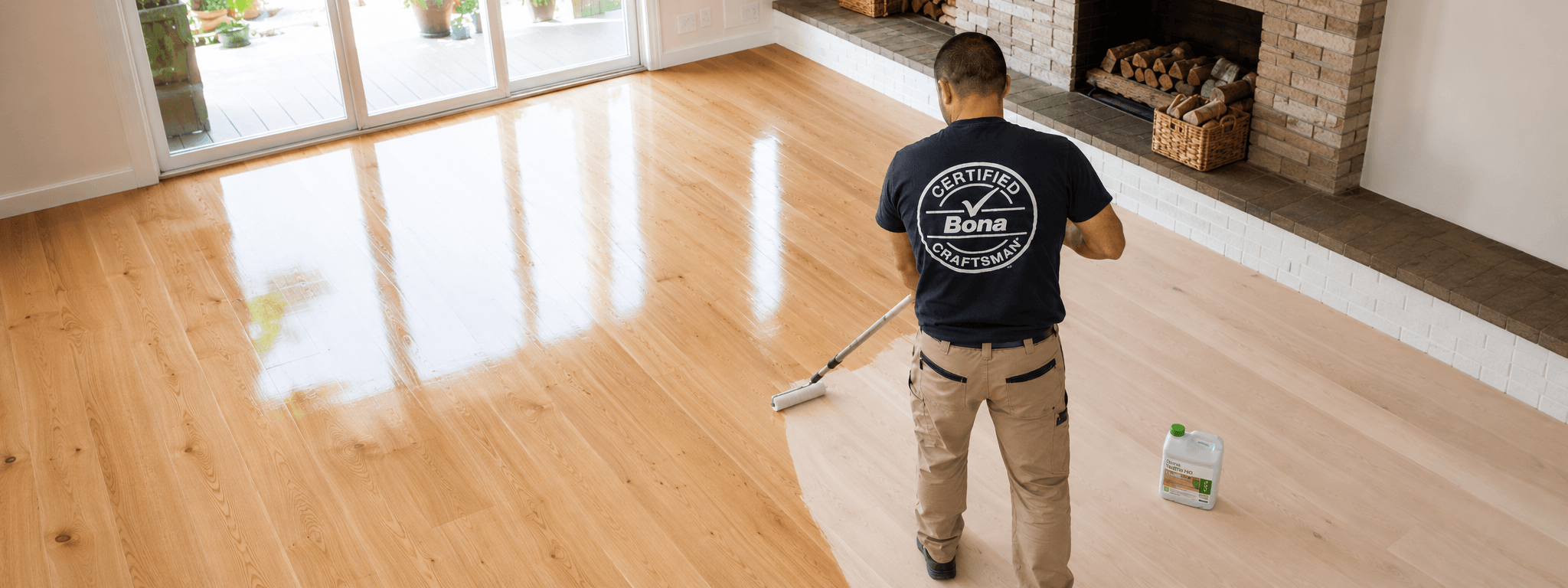 Bona Certified Craftsman varnishing a wooden floor with a roller in a home setting